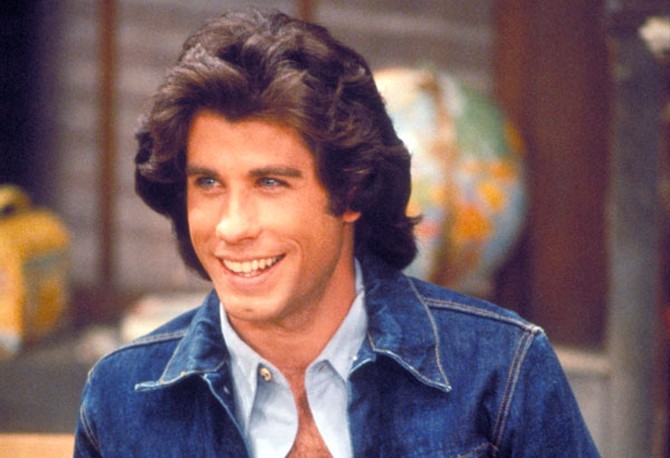 TV promo photo of a young man in a denim jacket smiling on a classroom set