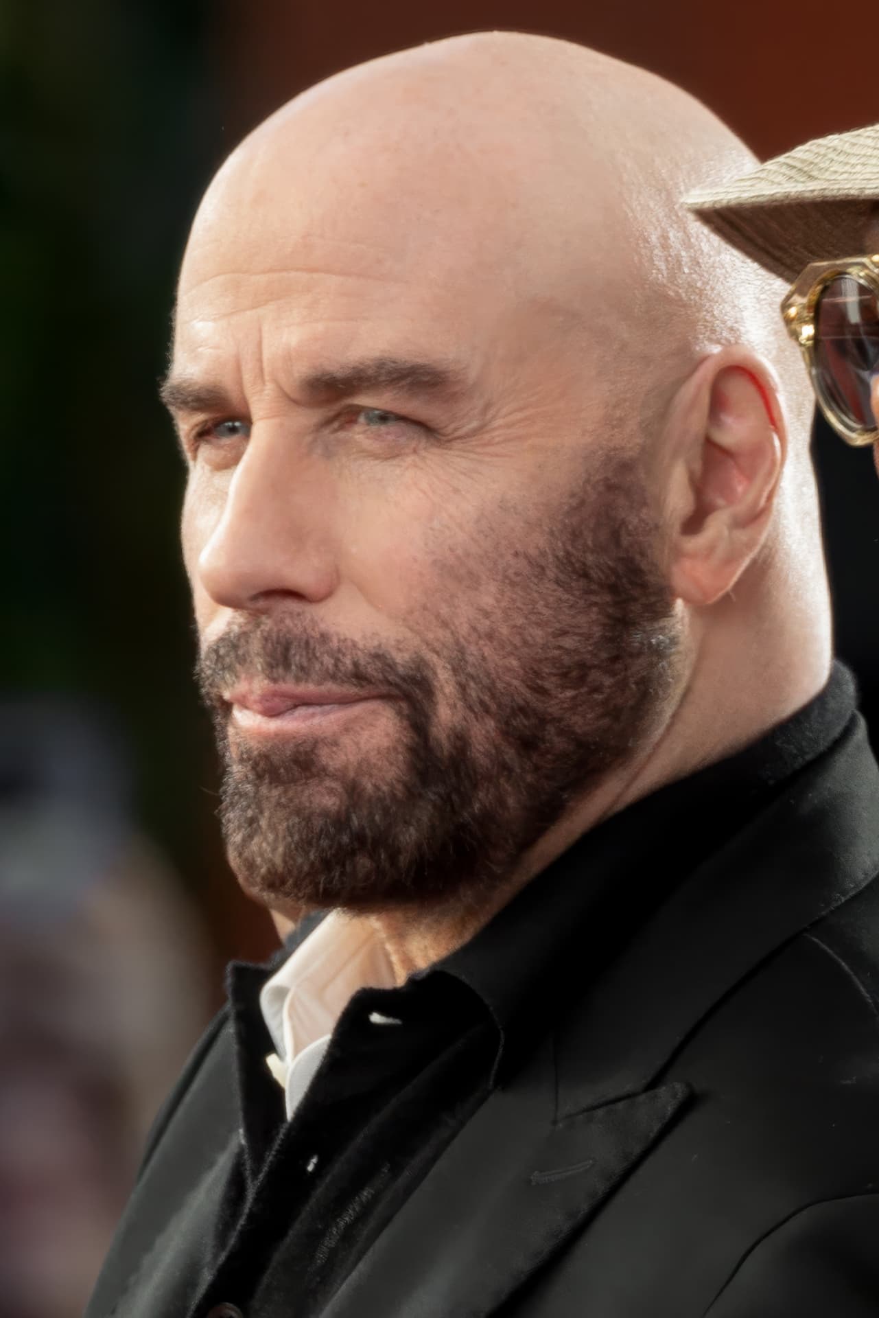Sharp close-up red-carpet photo of a man in his mid-sixties smirking off-camera